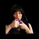 Woman using a purple cannabis pipe.