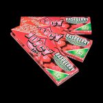 A brightly lit, close-up view of Juicy Jay's Classic Size Flavored Rolling Papers with a vibrant raspberry design.