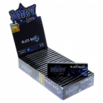 A close-up of Juicy Jay's 1 1/4 Black Magic Rolling Papers packaging, with the black pack angled slightly toward the viewer.