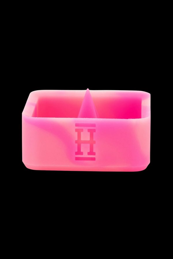Pink silicone cannabis concentrate container with a geometric logo.