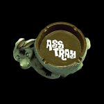 A ceramic ashtray shaped like a coiled snake with “ASS TRAY” written on its surface, set against a black background.