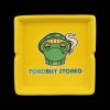 Yellow ashtray featuring a cartoon frog wearing a mushroom cap and exhaling smoke, with the text "TOADALLY STONED."
