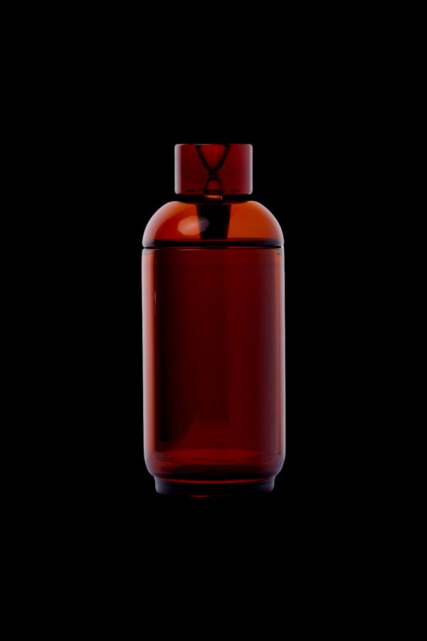 Amber glass cannabis oil vial with a unique hourglass-shaped stopper, isolated on a black background.