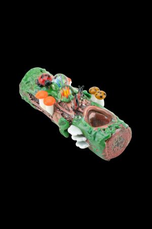 Hand-blown glass pipe sculpted as a whimsical forest log with colorful mushrooms, flowers, and a smiling face.