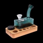 Teal glass water pipe (rig) on a wooden base with storage for accessories.