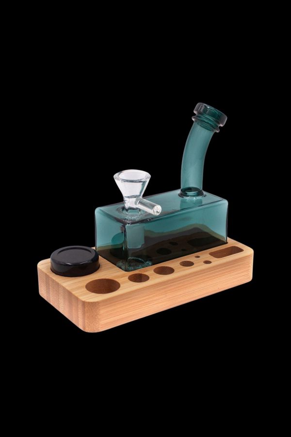 Teal glass water pipe (rig) on a wooden base with storage for accessories.