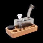 Glass bubbler on a wooden base with storage for accessories.