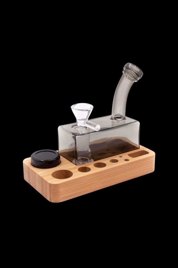 Glass bubbler on a wooden base with storage for accessories.