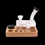 Clear glass dab rig with wooden base and accessories.