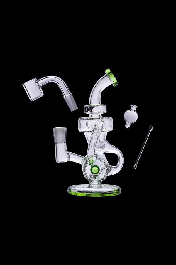Clear glass dab rig with green accents, including a quartz banger, carb cap, and dab tool, isolated on a black background.