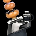 A black and silver portable vaporizer with a colorful glass bubbler attachment.