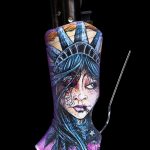 A lighter sleeve depicting a stylized, melancholic portrait of Lady Liberty, alongside a black lighter and metal tool, against a black background.