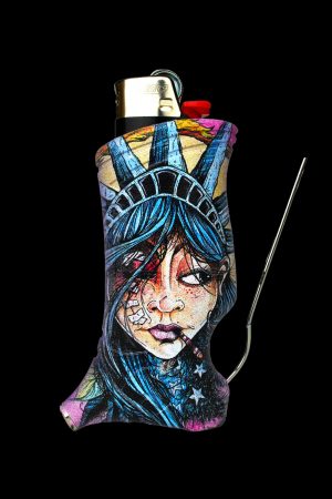 A lighter sleeve depicting a stylized, haunting portrait of Lady Liberty with cannabis leaves and stars, paired with a metal dab tool against a black background.