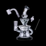 Clear glass dab rig with accompanying nail, carb cap, and dab tool, isolated on a black background.