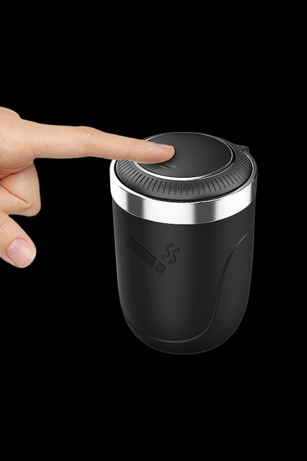 Close-up of a hand pressing the button on a black cannabis grinder.