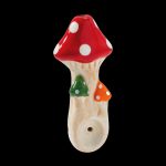 Ceramic mushroom-shaped pipe with red and white spotted cap, against a black background.