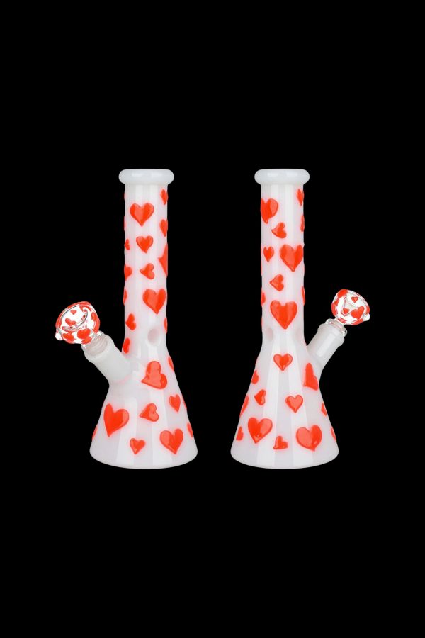 Two white glass bongs decorated with red hearts against a black background.