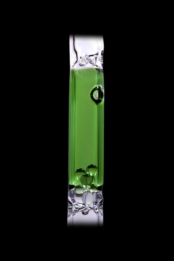 Green cannabis oil filling a glass pipe against a black background.