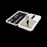 Digital scale with a small metal cylinder on the weighing platform, open on a clear plastic case.