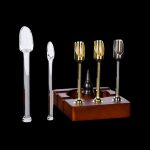 Cannabis oil rig with glass tips and wooden base on a black background.