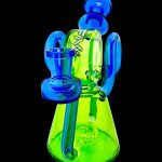 A colorful glass water pipe (bong) with blue and green hues, featuring looped handles and a flared base.