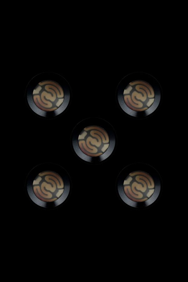 Five metallic cannabis oil cartridge caps with embossed swirling designs against a black background.