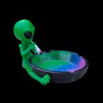Green alien sculpture holding a glowing ashtray.