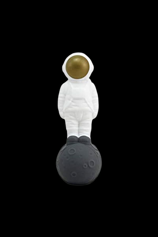 Astronaut figurine standing on a textured, dark sphere, likely a cannabis accessory.
