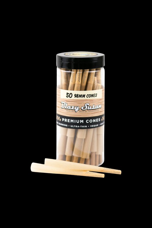 A clear plastic tube filled with 50 unlit, rolled paper cones for smoking, labeled "Blazy Susan Premium Cones." One cone is laid out beside the tube.