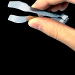Silver cannabis trimming scissors held in a hand, against a black background.