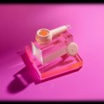 Pink glass cannabis pipe and concentrate on acrylic display, illuminated with pink light.