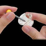 Hand applying a dab tool to a clear quartz banger.